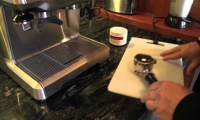 A Man Cleaning a Coffee Machine with a Tablet